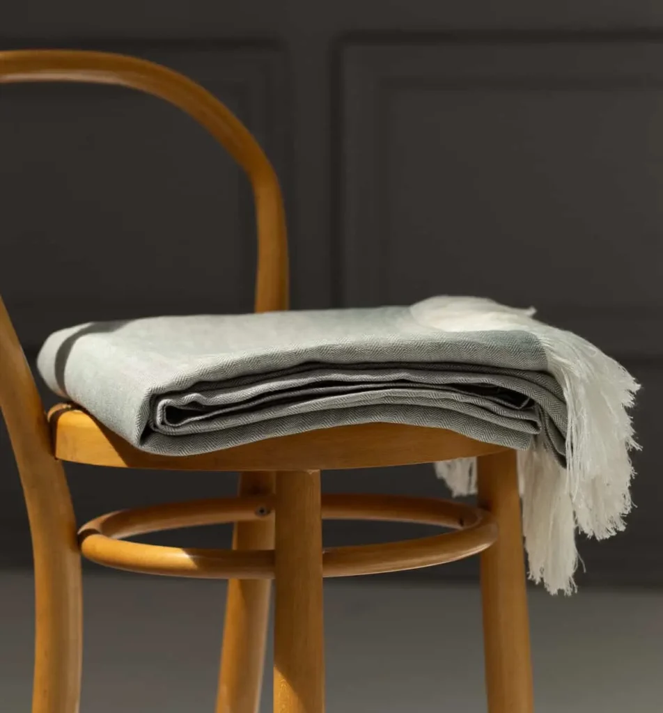 A linen throw nicely folded and arranged on a chair.